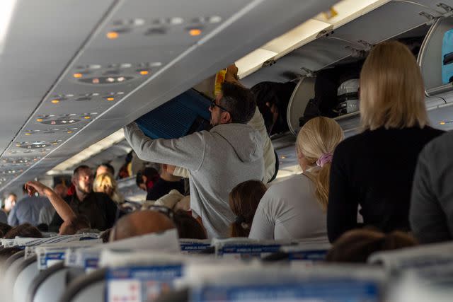 <p>Getty</p> Passengers standing in the aisle of an airplane