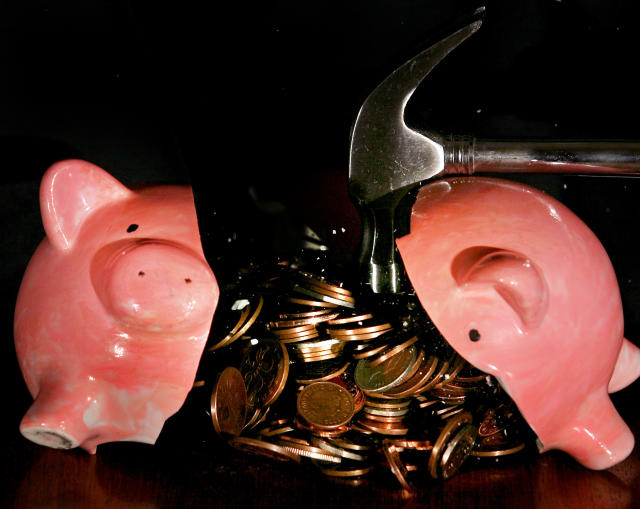 A traditional piggy bank is smashed open with a hammer. Photo: Anthony Devlin /PA