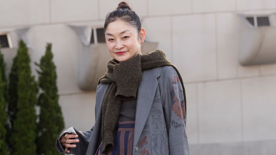 Fsahion Week attendee Reishito seen wearing a blue wool coat and stripped pants with a scarf and floral bag. - Matt Jelonek/Getty Images