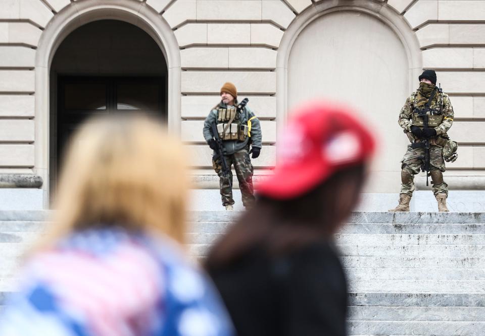 Two militia members keep watch at the front of Kentucky's state Capitol as about 40 people marched in honor of Ashli Babbitt, the Air Force veteran who was shot and killed by a U.S. Capitol Police officer on Jan. 6.