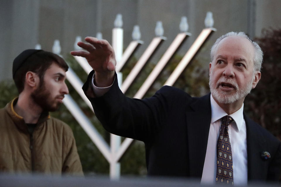 FILE - In this Dec. 2, 2018, file photo, Rabbi Jeffrey Myers, right and his son, Aaron, oversee the installation of a menorah outside the Tree of Life Synagogue before holding a celebration on the first night of Hanukkah in the Squirrel Hill neighborhood of Pittsburgh. When Pennsylvania Gov. Tom Wolf visits Holocaust memorials in Lithuania and Poland, he'll carry the mezuzah that was outside the office door of Rabbi Jeffrey Myers when a gunman killed 11 people in Pittsburgh's Tree of Life synagogue. Wolf said Friday, Sept. 6, 2019 that he called Myers ahead of his trip to the two countries, where he'll also visit Pennsylvania National Guard troops and meet with Lithuanian President Gitanas Nauseda. (AP Photo/Gene J. Puskar, File)