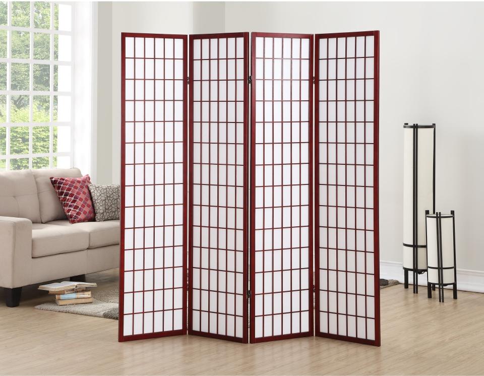 A four-panel wooden room divider with a grid design, standing in a living room