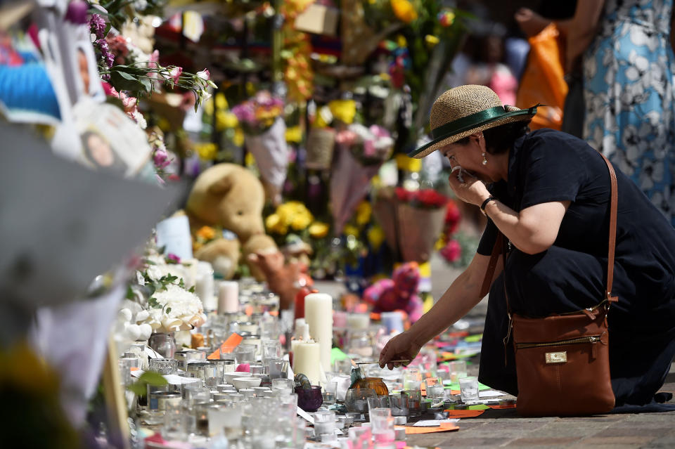 <p>A woman lights a candle at a spot where people have left tributes to those who perished in the Grenfell apartment tower block fire in North Kensington, London, Britain, June 17, 2017. (Hannah McKay/Reuters) </p>