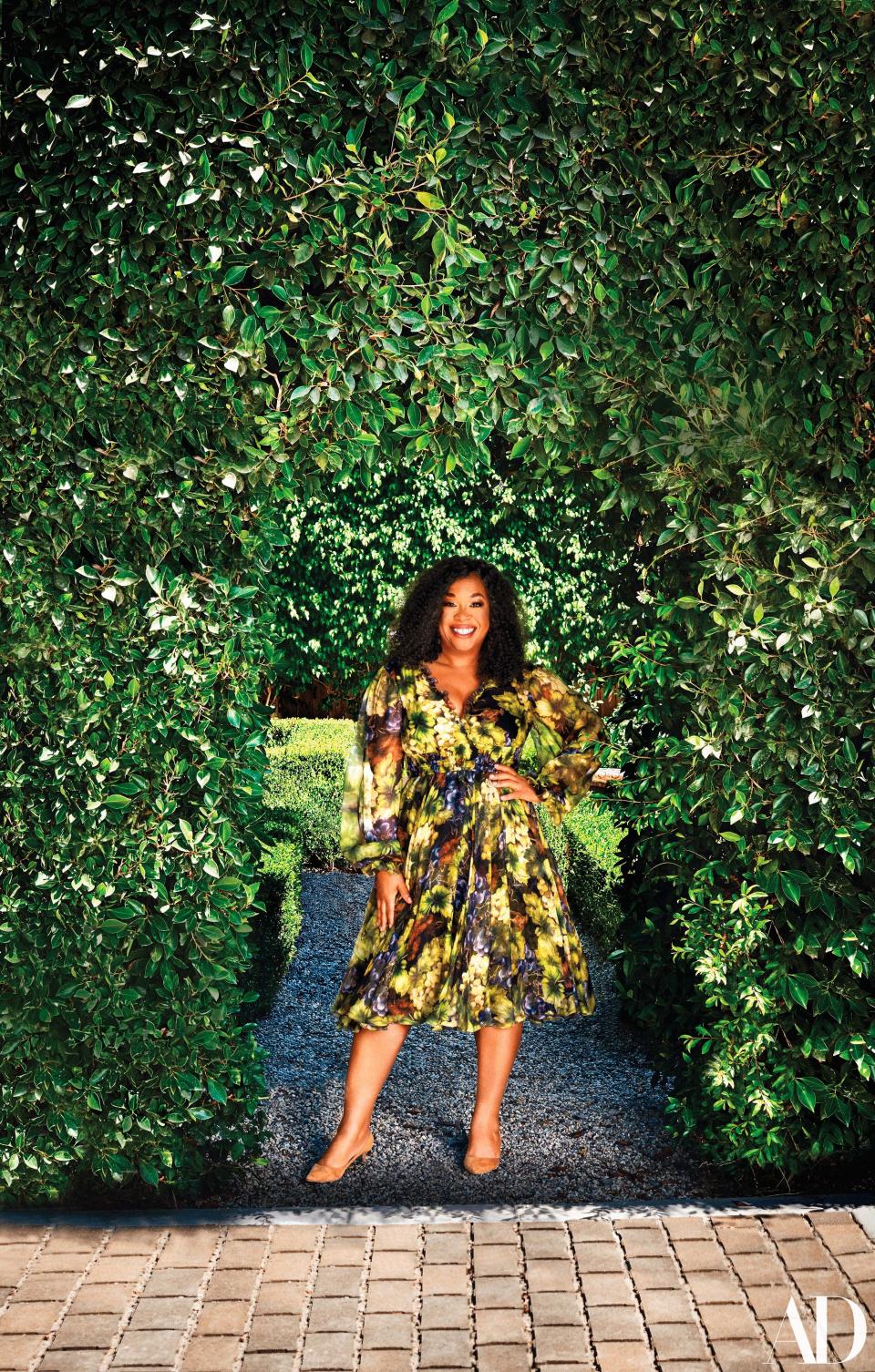 Shonda Rhimes, wearing a Dolce & Gabbana dress and Jimmy Choo shoes, in her garden.