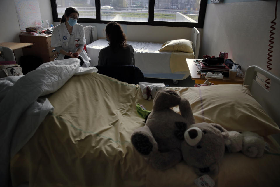 Psychiatrist Coline Stordeur speaks with a young girl in her room in the pediatric unit of the Robert Debre hospital, in Paris, France, Tuesday, March 2, 2021. Doctors say the impact of the coronavirus pandemic on the mental health of children is alarming and plain to see. (AP Photo/Christophe Ena)