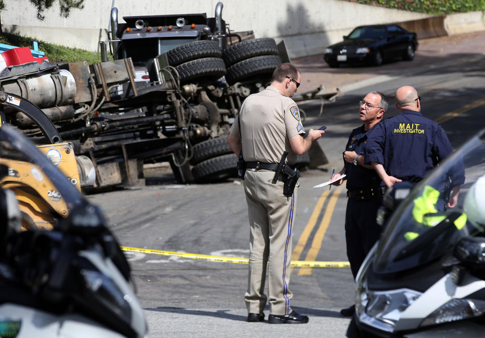 Officials investigate the scene of a wreck Friday March 7, 2014 where a Los Angeles police officer was killed and another critically injured, when their cruiser was struck by a big rig at a Beverly Hills, Calif., intersection LAPD Officer Rosario Herrera says the collision occurred shortly before 8 a.m. Friday at Robert Lane and Loma Vista Drive, in a residential area of the city. (AP Photo/Nick Ut )