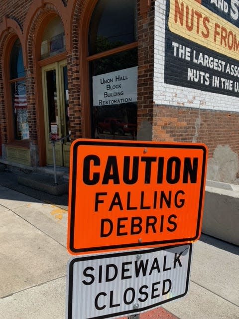 Signs showing the sidewalk is closed in front of the Tasty Nut Shop building in downtown White Pigeon.