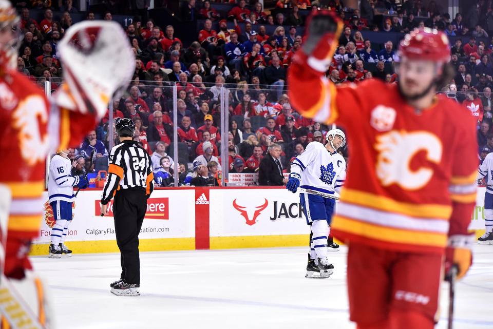 CALGARY, AB - DECEMBER 12: Toronto Maple Leafs Center John Tavares (91) looks on as Calgary Flames Goalie David Rittich (33) gets a high five from Calgary Flames Defenceman Rasmus Andersson (4) following a save during the third period of an NHL game where the Calgary Flames hosted the Toronto Maple Leafs on December 12, 2019, at the Scotiabank Saddledome in Calgary, AB. (Photo by Brett Holmes/Icon Sportswire via Getty Images)