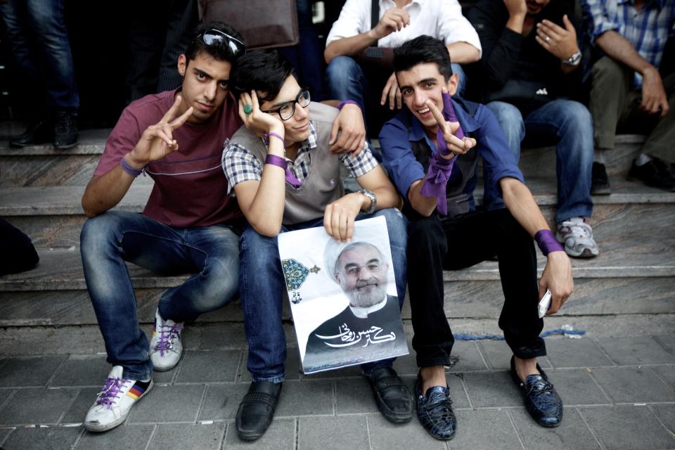 Iranians supporters of moderate presidential candidate, Hassan Rouhani flash the sign of victory holding a portrait of him as they wait for the final results outside his campaign headquarter in downtown Tehran on June 15, 2013. Rouhani has a clear lead in Iran's presidential election, garnering 51 percent of the vote at 65 percent of polling stations across the country, the interior ministry said. (BEHROUZ MEHRI/AFP/Getty Images)