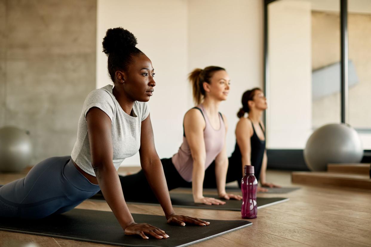 Athletic women doing stretching wile exercising on group training in a gym. Focus is on African American woman.