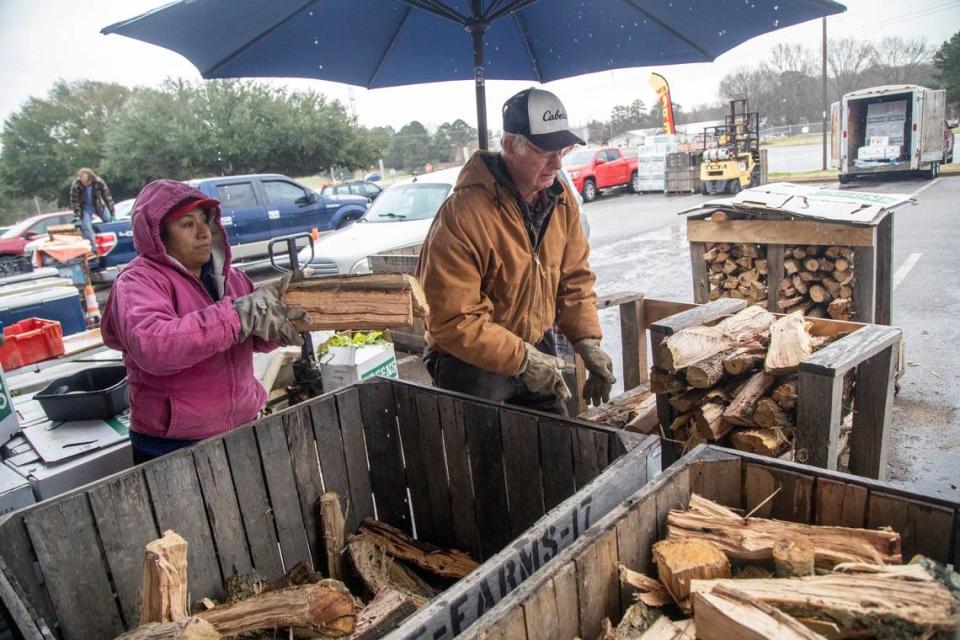 Gladys Calles and William Wise of Wise Farms load bins with firewood Thursday morning, Jan. 20, 2022. at the North Carolina State Farmers Market in Raleigh. The National Weather Service has issued a Winter Storm Watch for all of central North Carolina as the Triangle braces for the second winter blast in less than a week.