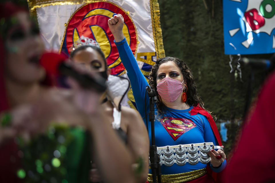 Una mujer vestida como Superchica y con una mascarilla para protegerse del coronavirus alza un puño durante el espectáculo de la banda "Desliga da Justica" el domingo 14 de febrero de 2021, en Río de Janeiro, Brasil. (AP Foto/Bruna Prado)