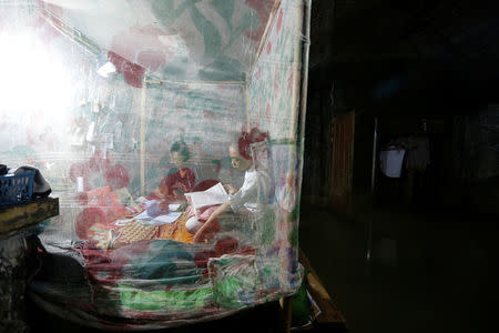 Sriwarsih, a student, reads a book in her bed as rising sea water hits her house in Bedono village in Demak, Indonesia, February 1, 2018. REUTERS/Beawiharta