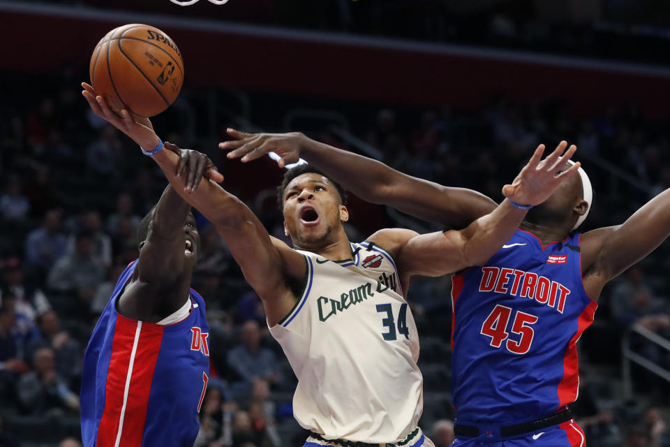 Milwaukee Bucks forward Giannis Antetokounmpo (34) makes a layup as Detroit Pistons forwards Thon Maker, left, and Sekou Doumbouya (45) defend during the first half of an NBA basketball game, Thursday, Feb. 20, 2020, in Detroit. (AP Photo/Carlos Osorio)