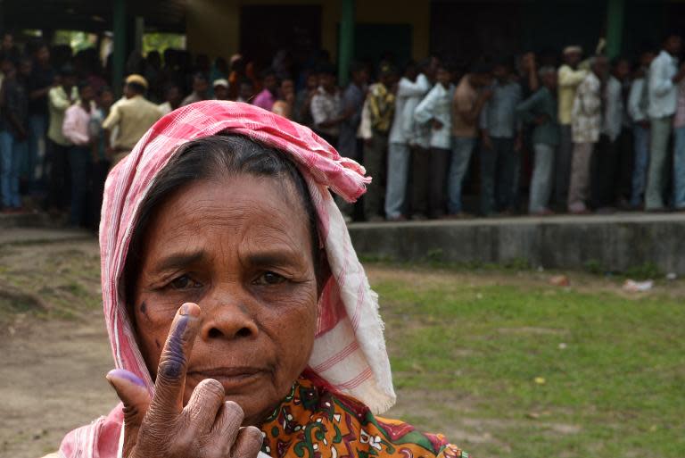 An Indian voter shows her inked finger after voting outside a polling station in Dibrugarh on April 7, 2014