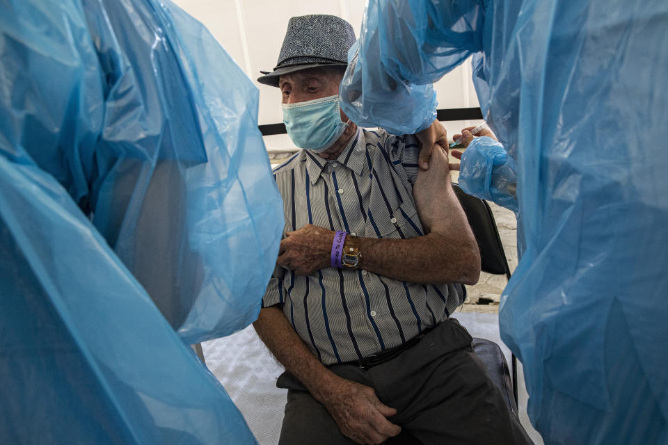 Alejandro Pavez, 91, receives a dose of China's Sinovac Biotech COVID-19 vaccine at a vaccination center set up at the Bicentenario Stadium in Santiago, Chile, Wednesday, Feb. 3, 2021. Chile is starting its vaccination plan for the general population on Wednesday with seniors over 90 and health workers. (AP Photo/Esteban Felix)