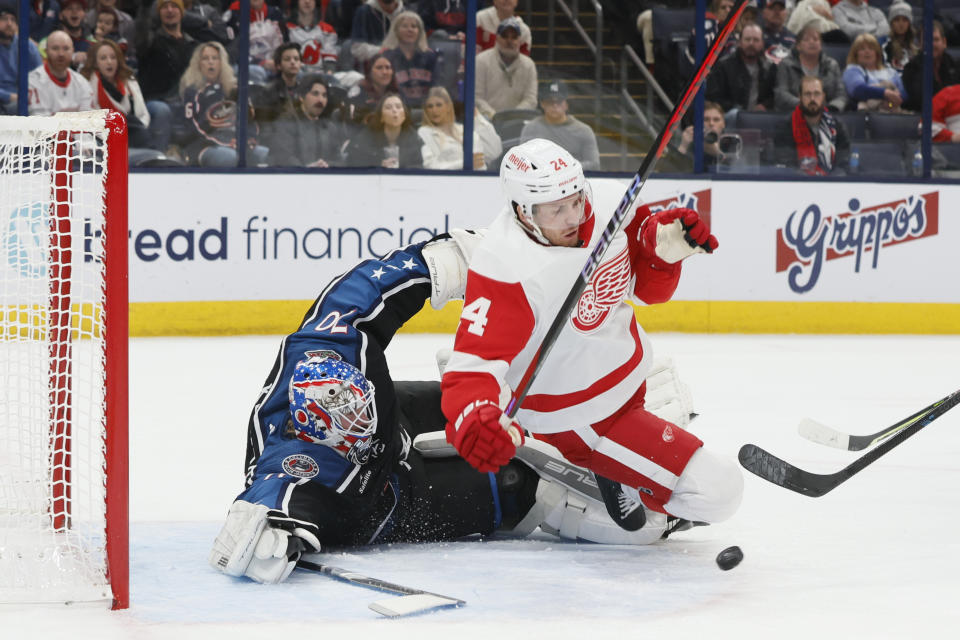 Columbus Blue Jackets' Joonas Korpisalo, left, makes a save as Detroit Red Wings' Pius Suter collides with him during the first period of an NHL hockey game on Sunday, Dec. 4, 2022, in Columbus, Ohio. (AP Photo/Jay LaPrete)