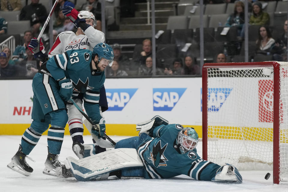 Washington Capitals right wing Anthony Mantha, top, and San Jose Sharks defenseman Nikita Okhotiuk (83) watch as goal scored by Capitals' Evgeny Kuznetsov gets past Sharks goaltender Mackenzie Blackwood, bottom, during the second period of an NHL hockey game in San Jose, Calif., Monday, Nov. 27, 2023. (AP Photo/Jeff Chiu)