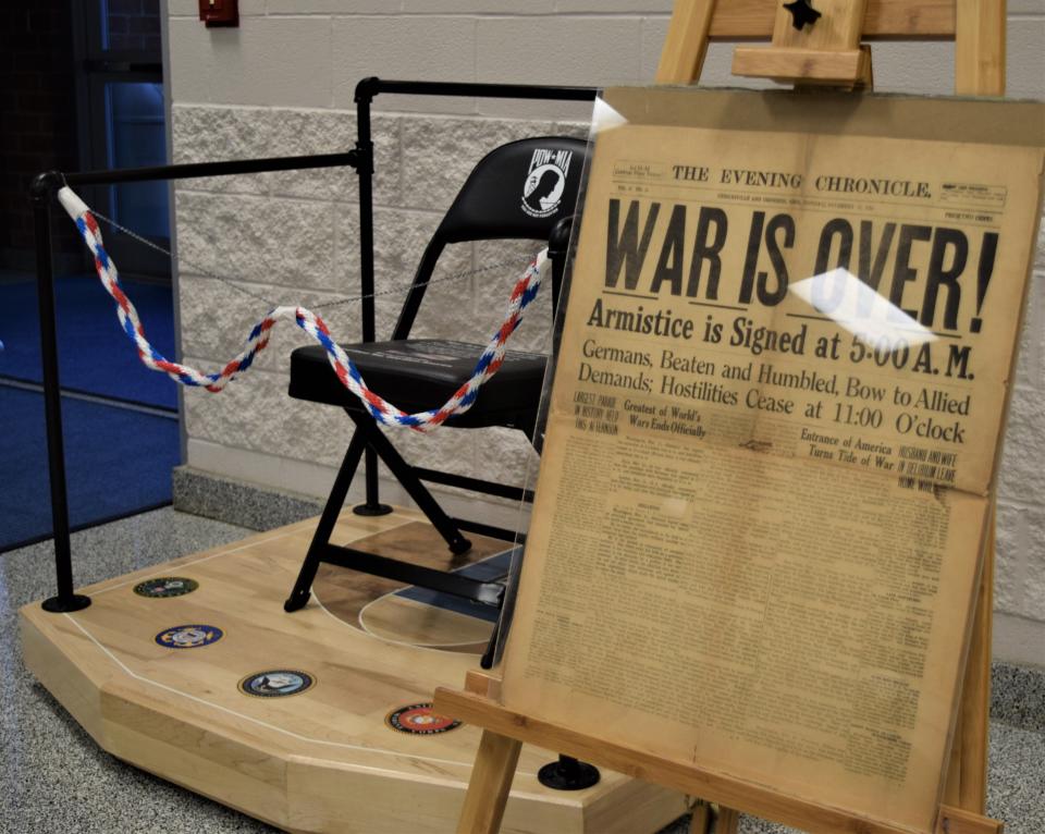 Artifacts on display in the commons area at West Holmes High School include a newspaper headline from 1918 declaring the end of World War I and a Chair of Honor remembering the Prisoners of War and those Missing in Action.