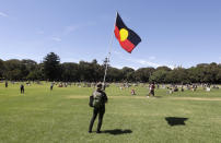 A man holds an Aboriginal flag in a social distanced crowd during an Aboriginal-lead Invasion Day rally on Australia Day in Sydney, Tuesday, Jan. 26, 2021. Many of Australia's First Nations people say that sovereignty has never been ceded and oppose ongoing colonial violence and destruction. (AP Photo/Rick Rycroft)