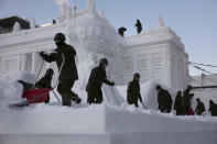 Self-Defense Force members remove fresh snow piled on a large snow sculpture of Poland's Palace on the Isle during the Sapporo Snow Festival at Odori Park in Sapporo, Hokkaido, Japan, Feb. 6, 2020. Sapporo hosted the Winter Olympics back in 1972. (AP Photo/Jae C. Hong)