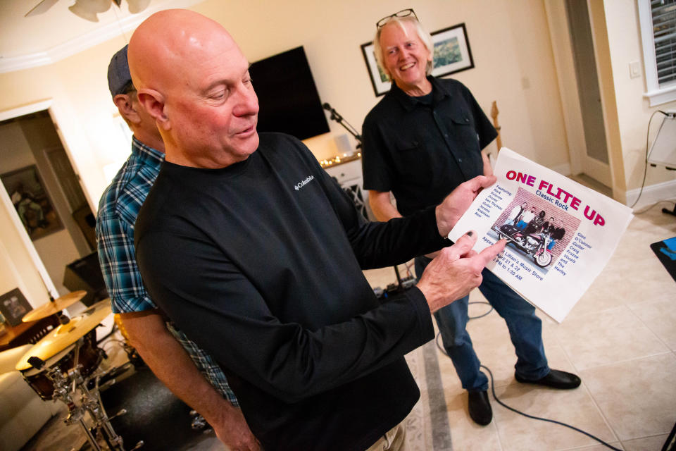 One Flite Up guitarist Kenny Thomas, left, shows off an old flyer of the band from the early 2000s.