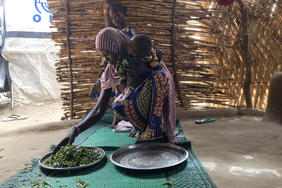 Iza Ali, 25, selects vegetables to prepare a meal for her family at the Jere camp for people displaced by Islamist extremists in Maiduguri, Nigeria, Wednesday, May 4, 2022. Iza Ali's five children are still waiting to eat at 3 p.m. It's not the first day that the family has gone without food since they fled extremist violence in northeast Nigeria six years ago. She and her husband scrape together $3 a day, but it's rarely enough to feed the family of seven. Often they scavenge for greens outside the Jere displacement camp where they live on the outskirts of Maiduguri. (AP Photo/Chinedu Asadu)