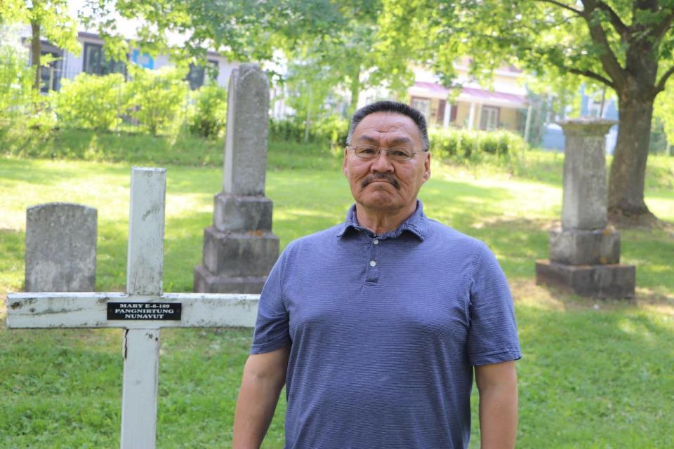 Joanasie Akumalik standing in front of one of the few marked Inuit graves in the Mount Hermon Cemetery in Quebec City.