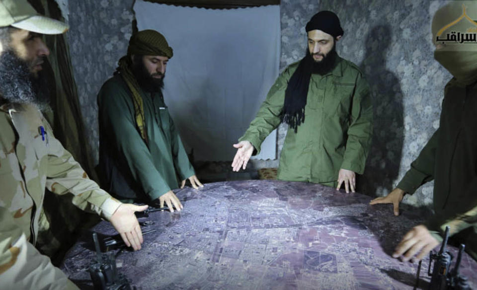 FILE - This undated file photo released by a militant group in 2016, shows Abu Mohammed al-Golani of the militant Levant Liberation Committee and the leader of Syria's al-Qaida affiliate, second right, discussing battlefield details with field commanders over a map, in Aleppo, Syria. Intermingled among 3 million civilians under siege in the Syrian government's assault on the last opposition stronghold are tens of thousands of al-Qaida-linked fighters and other militants who came from around the world to take part in the country's civil war. (Militant UGC via AP, File)