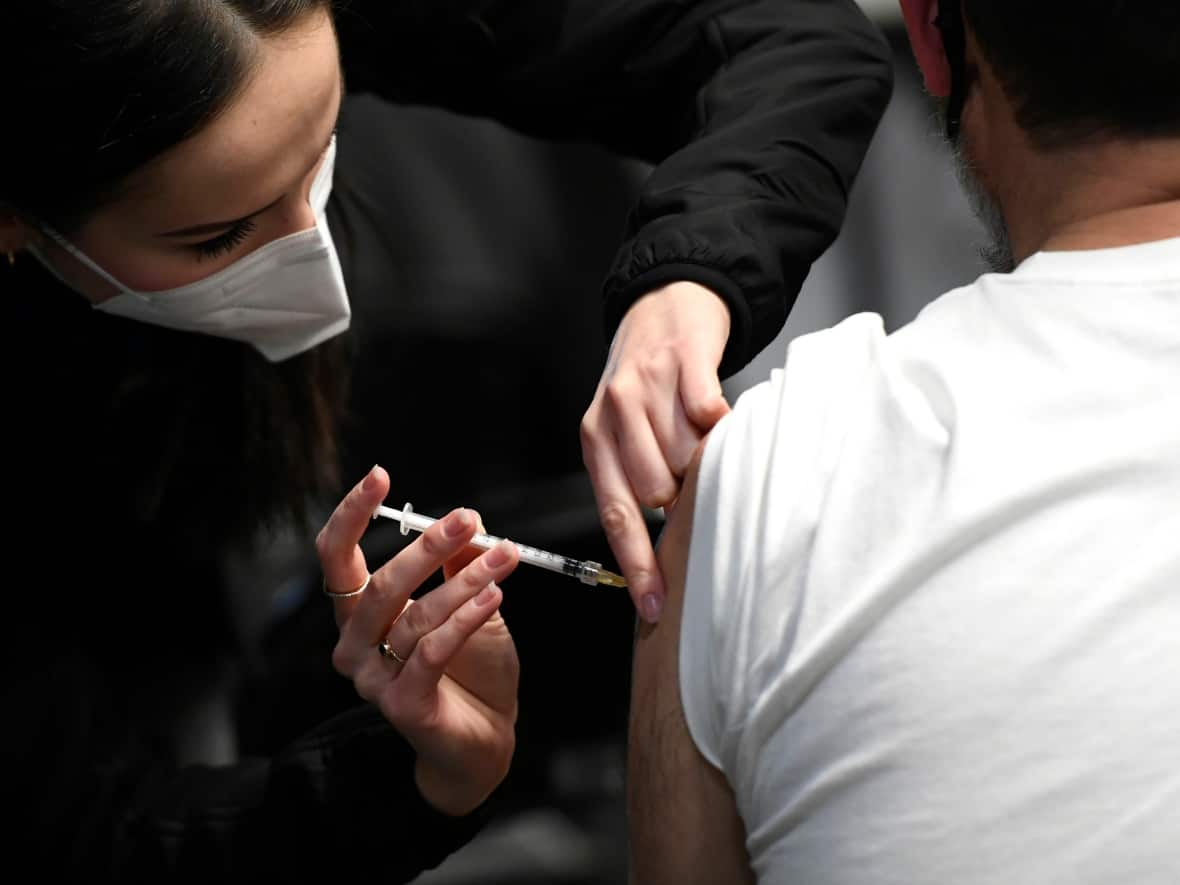 Medical student Nina Hadzimustafic delivers a COVID-19 shot at a the Jabapalooza pop-up vaccine clinic in Ottawa Dec. 20, 2021. The clinic delivered boosters to essential workers, and included teachers in that definition.  (Justin Tang/The Canadian Press - image credit)