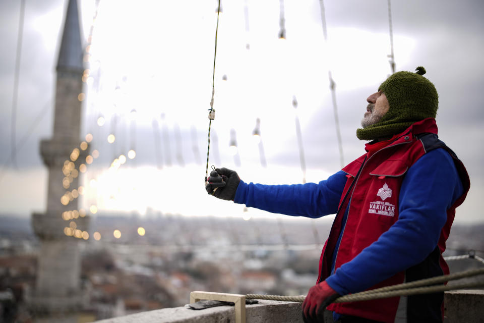 Mahya master Kahraman Yildiz works in the installation of a lights message at the top of one of the minarets of the Suleymaniye mosque ahead of the Muslim holy month of Ramadan, in Istanbul, Turkey, Wednesday, March 6, 2024. Yildiz, a master of Mahya, the unique Turkish tradition of stringing religious messages and designs between minarets, is facing the twilight of a practice deeply ingrained in Turkish culture that is also taken for granted. (AP Photo/Emrah Gurel)