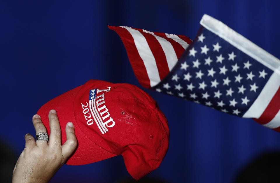 A support holds up a Trump 2020 hat and an American flag as Vice President Mike Pence speaks during a rally on Tuesday, June 25, 2019 in Miami. (AP Photo/Brynn Anderson)