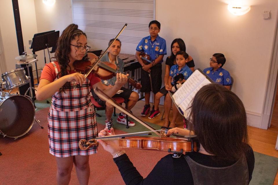 Citlalli Marin Rivera, 12 practices her violin with instructor Talia Pavia, chair of the conservatory's string department as members of her family watch. Citlalli along with siblings — Adrian Jesus, 11 and Cesar Gabriel, 7 — all received free violins from the conservatory, where they also take lessons.