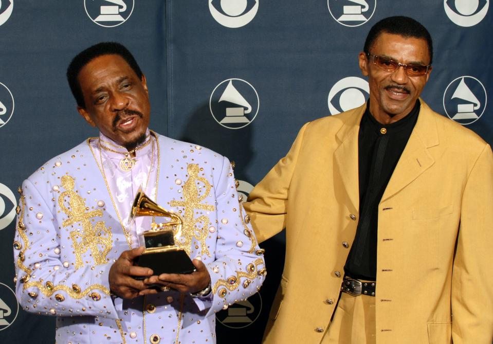 Ike and Turner Jr. posing together while holding a Grammy Award and wearing bright blazers.