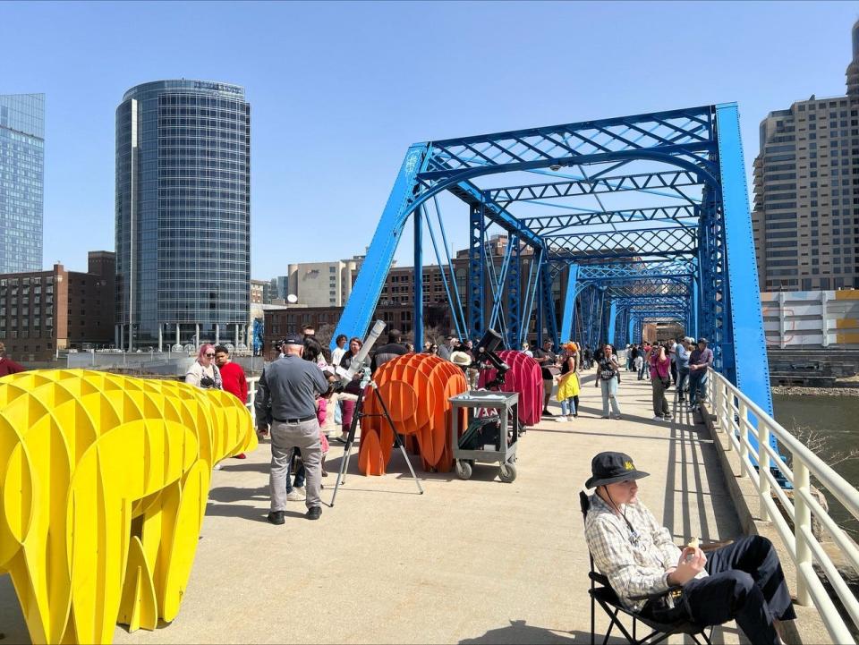 Visitors gather on the Blue Bridge to view the solar eclipse on Monday, April 8, 2024, in Grand Rapids. The Grand Rapids Public Museum provided a series of solar telescopes to view the eclipse through.