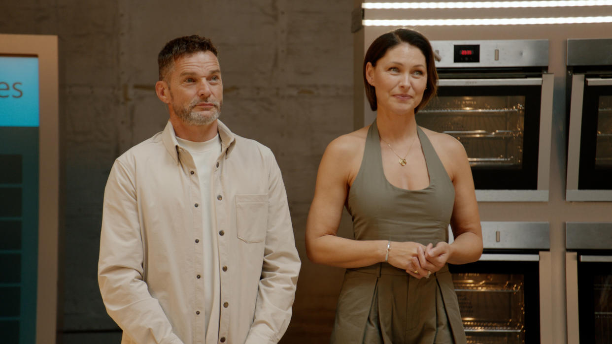  Fred Sirieix and Emma Willis stand in the studios of The World Cook's UK headquarters, with a wall of ovens behind them in the background. 