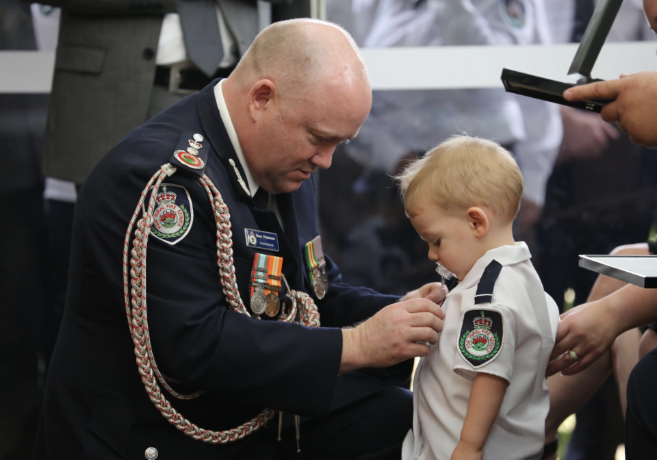 Mr Fitzsimmons is seen pinning Mr Keaton's bravery award on his young son Harvey’s shirt. Source: RFS 