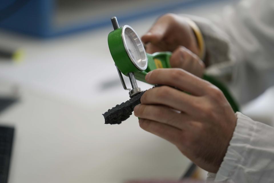 A worker checks a piece of the athletics track, at the Mondo factory, in Alba, northern Italy, Wednesday, March 13, 2024. The athletics track for the upcoming Paris Olympics is being produced by the Mondo company at its factory in northern Italy. The track is made in portions, rolled up and then will be transported to the Stade de France, where it will be installed over the next month. (AP Photo/Luca Bruno)