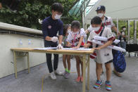 Fans wearing face masks to help protect against the spread of the new coronavirus check a list as they arrive to watch the KBO league game between Doosan Bears and LG Twins in Seoul, South Korea, Sunday, July 27, 2020. Masked fans hopped, sang and shouted cheering slogans in baseball stadiums in South Korea on Sunday as authorities began bringing back spectators in professional sports games amid the coronavirus pandemic. (AP Photo/Ahn Young-joon)