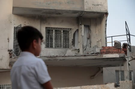 A boy stands in front of an apartment building which was damaged by a rocket fired from Syria, in Nusaybin