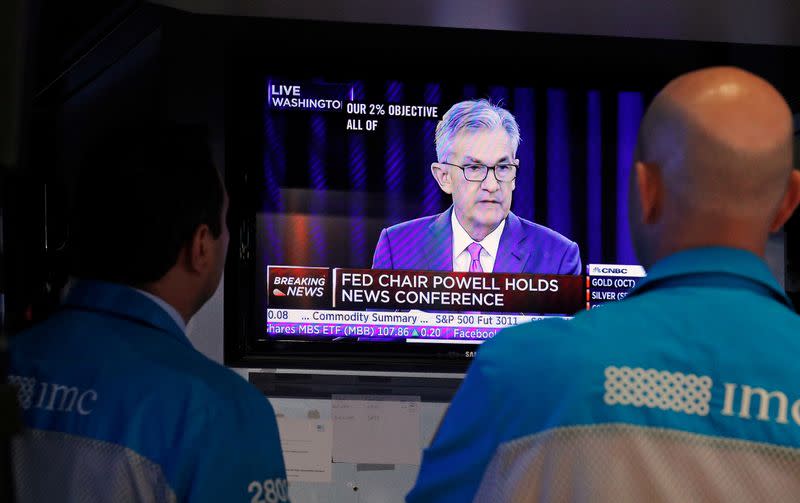 FILE PHOTO: Traders look on as a screen shows Federal Reserve Chairman Jerome Powell's news conference after the U.S. Federal Reserve interest rates announcement on the floor of the New York Stock Exchange (NYSE) in New York