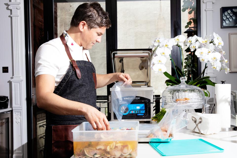 Photo of David Burka using a vacuum sealer to prepare chicken breasts for the sous vide.