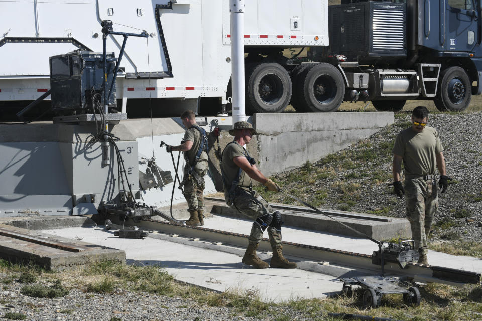 In this image provided by the U.S. Air Force, Airman 1st Class Jonathan Marrs, 21, left, and Senior Airman Jacob Deas, 23, right, work to dislodge the 110-ton cement and steel blast door covering the top of the Bravo-9 nuclear missile silo at Malmstrom Air Force Base, Mont., Aug. 24, 2023. When the first 225-pound aluminum tow, or "mule" could not pull the door open, Marrs dragged down a second tow to give them more power. (John Turner/U.S. Air Force via AP)