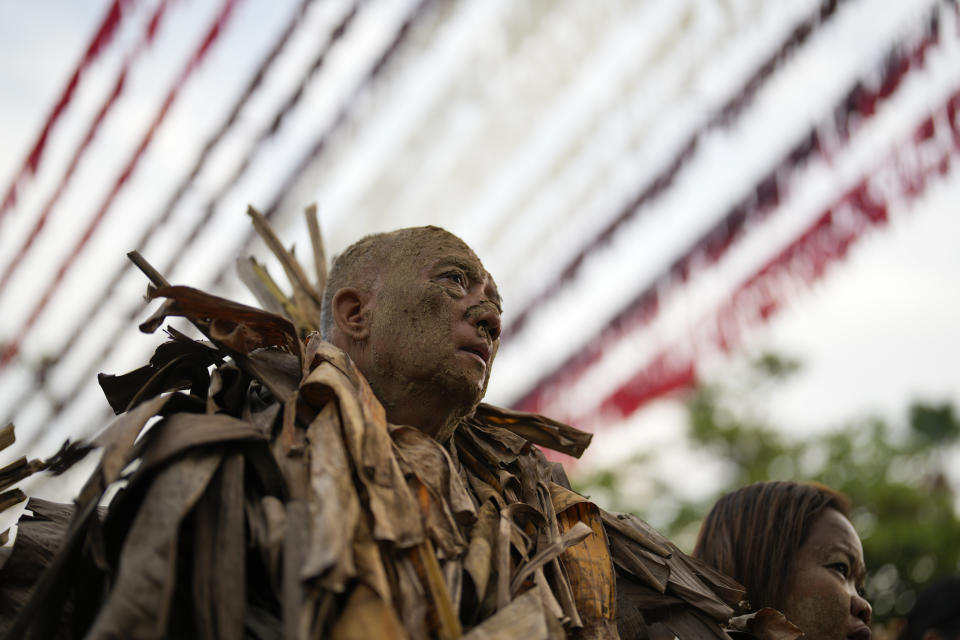 A devout Catholics, dressed in dried banana leaves, pray outside church of Saint John the Baptist during the mud festival at Bibiclat, Nueva Ecija province, northern Philippines, Monday, June 24, 2024. (AP Photo/Aaron Favila)