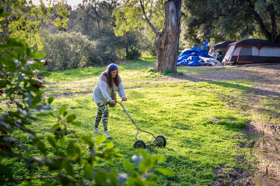 A woman mows grass at a homeless encampment in Ojai.