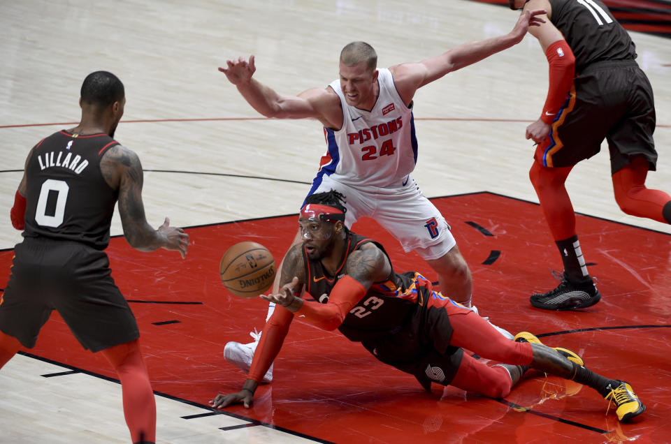 Portland Trail Blazers forward Robert Covington, center, passes the ball to guard Damian Lillard, left, as Detroit Pistons center Mason Plumlee defends during the first half of an NBA basketball game in Portland, Ore., Saturday, April 10, 2021. (AP Photo/Steve Dykes)