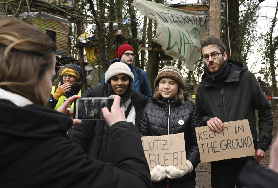 Climate activist Luisa Neubauer, left, takes a picture of climate activist Greta Thunberg, second right, during a visit of the village Luetzerath near Erkelenz, Germany, Friday, Jan. 13, 2023. The energy company RWE wants to excavate the coal lying under Luetzerath - for this purpose, the hamlet on the territory of the city of Erkelenz at the opencast lignite mine Garzweiler II is to be demolished. (Federico Gambarini/dpa via AP)