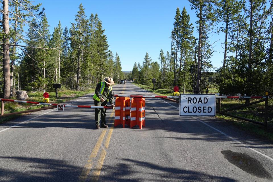 A park ranger unlocks the gates at the south entrance of Yellowstone National Park, which has been closed for more than a week, on June 22, 2022 in Yellowstone National Park, Wyoming