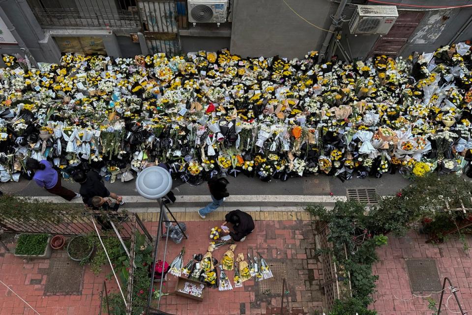 Residents walk by flowers laid outside a residential building where Li Keqiang spent his childhood in Hefei city (AP)