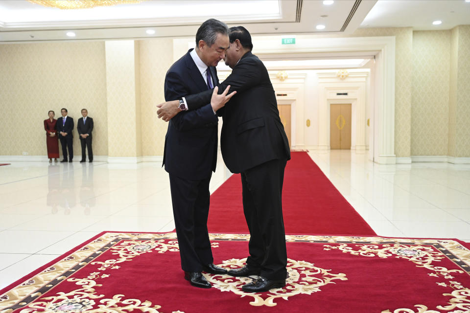 In this photo provided by Kok Ky/Cambodia's Government Cabinet, Cambodian Prime Minister Hun Sen, right, hugs Chinese Foreign Minister Wang Yi during a meeting in Peace Palace in Phnom Penh, Cambodia, Sunday, Aug. 13, 2023. (Kok Ky/Cambodia's Government Cabinet via AP)